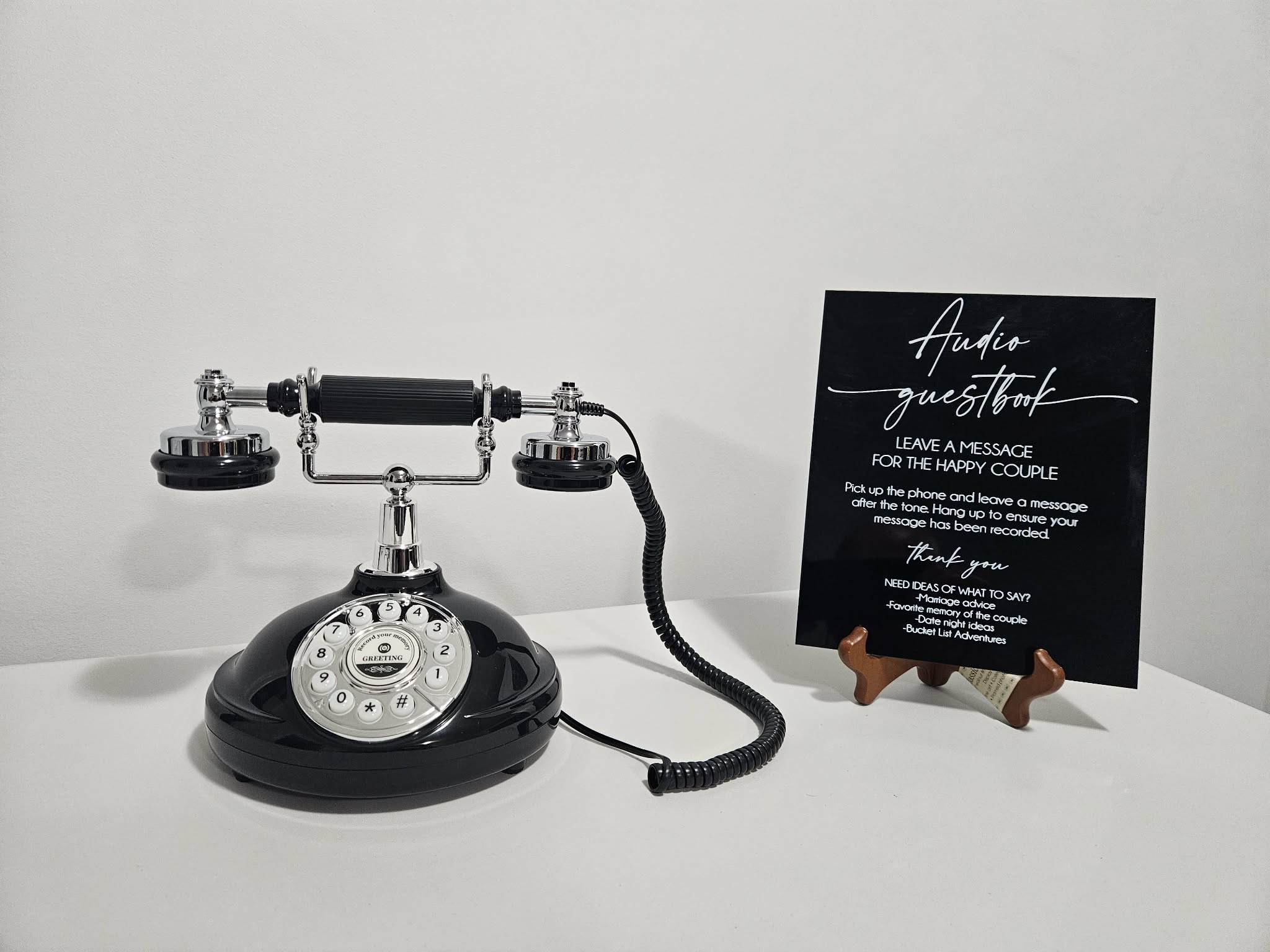 Black audio guestbook phone and black instruction sign for wedding guests