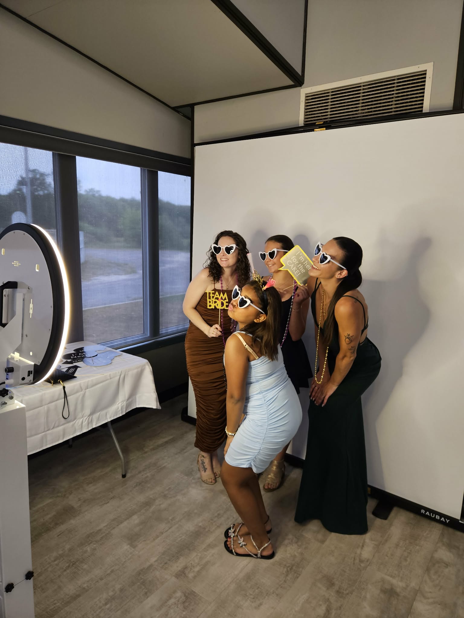 Ottawa wedding guests posing in a photo booth with Team Bride props and heart sunglasses